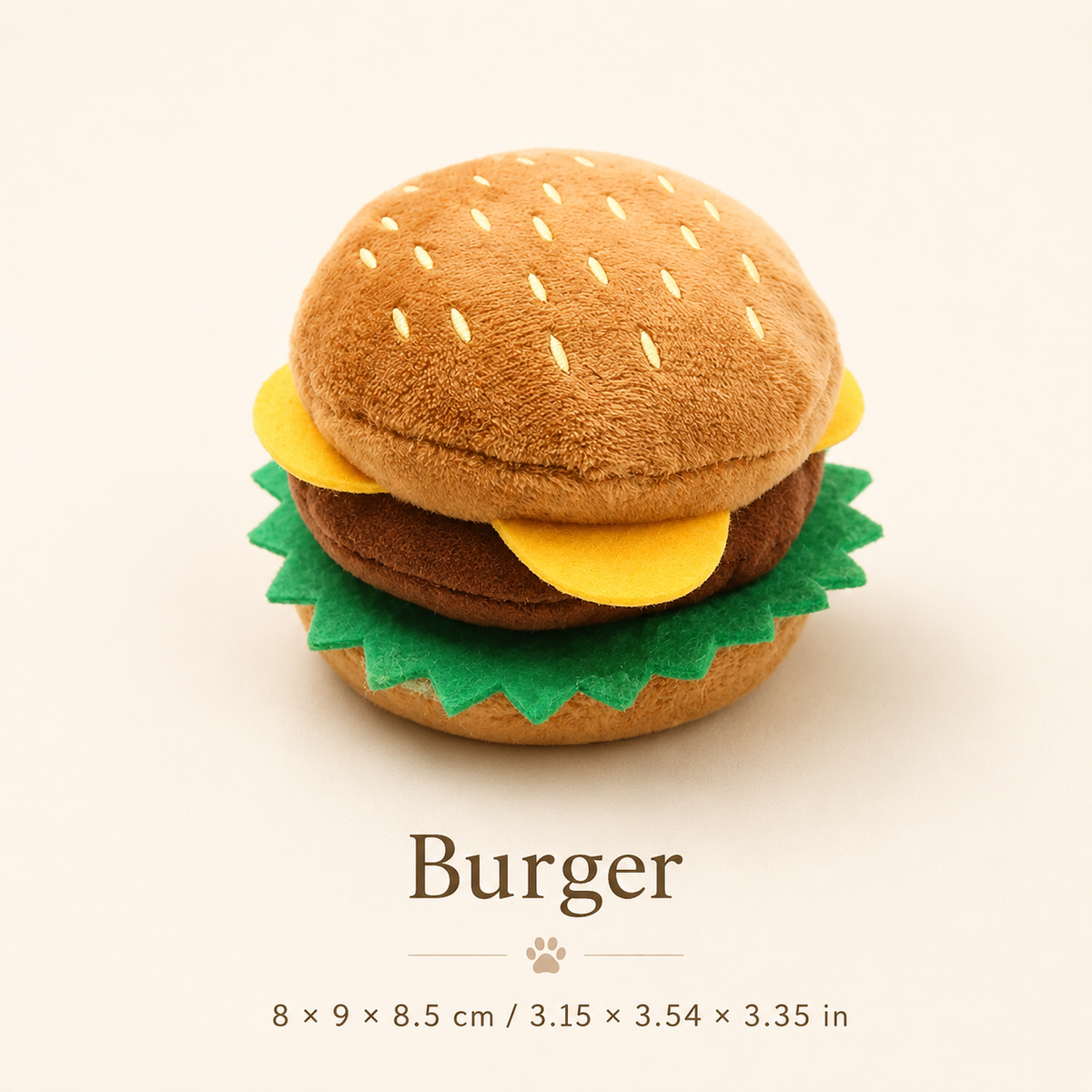 Burger-shaped plush squeaky dog toy shown on a soft ivory background with its dimensions in centimeters and inches.