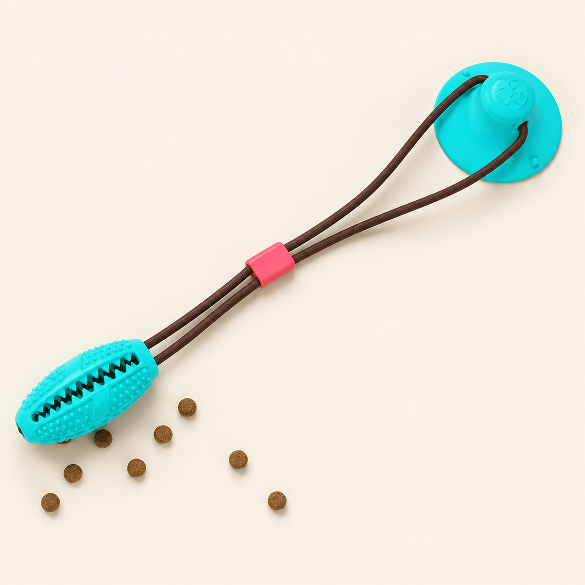 Blue suction cup dog tug toy with dual dark cords, pink cord slider and textured oval chew head on a warm ivory background.