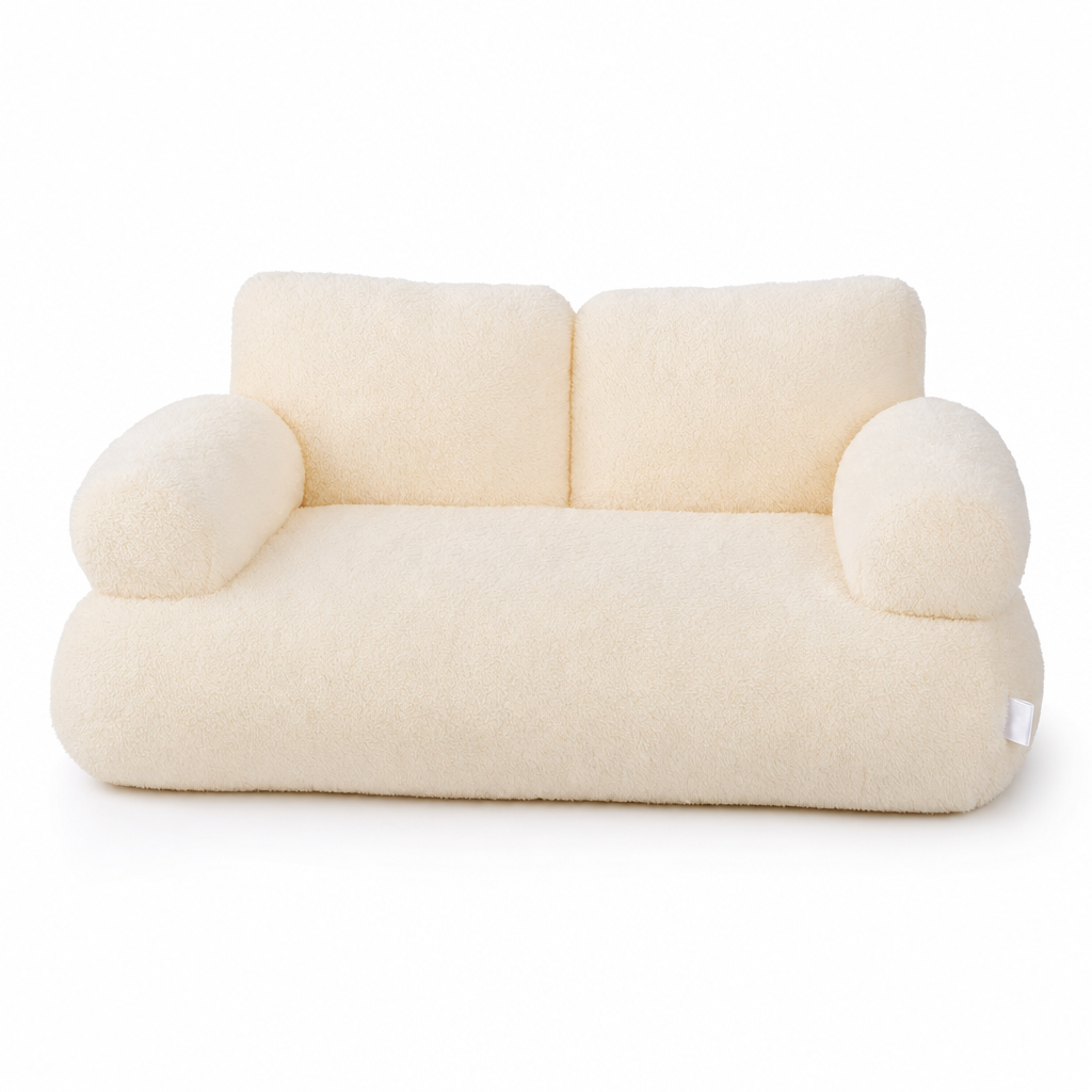 Cream plush cat bed shaped like a small sofa, with a two-part backrest and two rounded armrests.