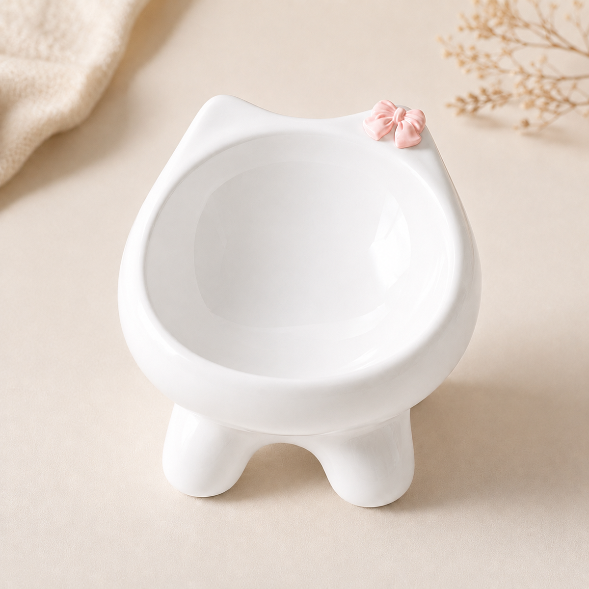 Pearl white Camellia Elevated Ceramic Cat Bowl with glossy glaze, rounded feet and pink bow accent on a warm neutral background.