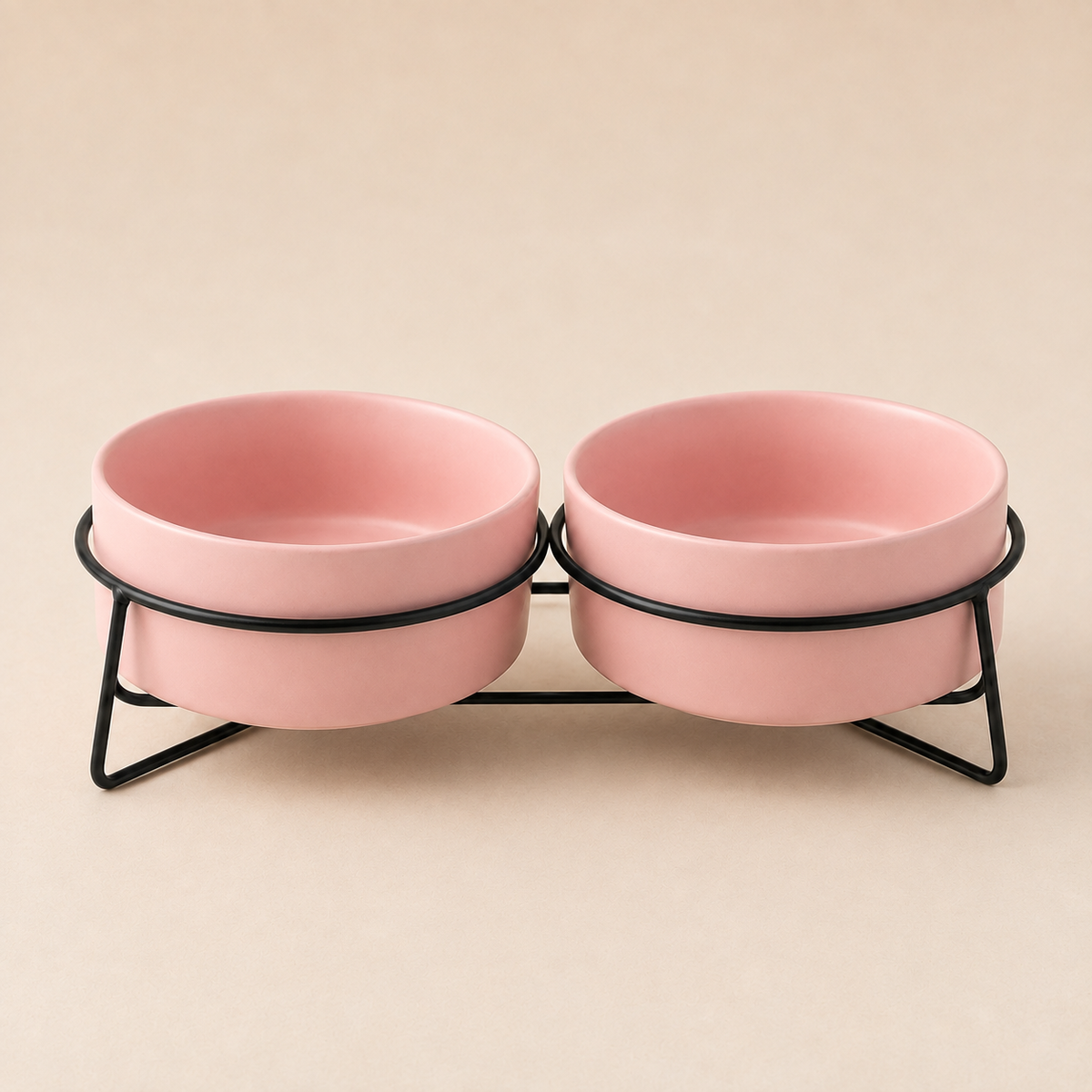 Double elevated pink ceramic pet bowls in a black metal stand on a soft neutral background.